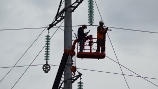 Workers on crane fixing electric power lines