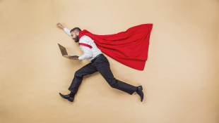Businessman in super hero pose wearing cape