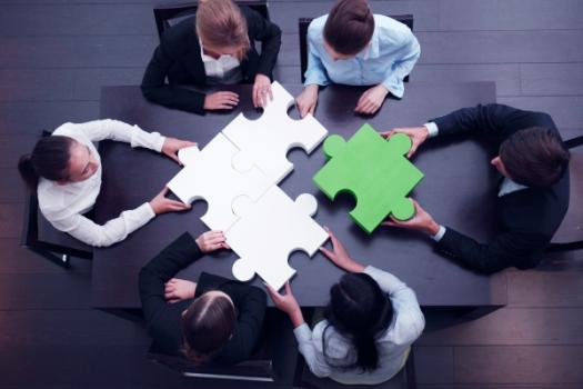 Employees at table solving giant puzzle