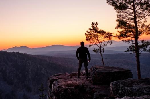 Person standing on cliff edge looking over it