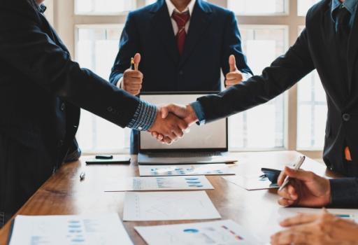 Two suits shaking hands in front of mediator