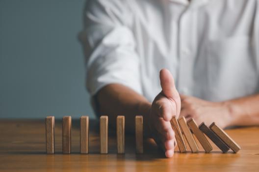 Hand stopping falling dominoes