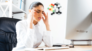 Businesswoman at computer with headache