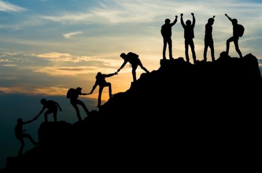 Team helping each other to top of mountain