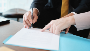 Woman pointing at contract for man to sign