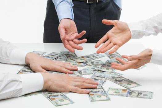Table of money with hands grabbing for it