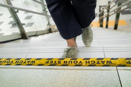 Woman climbing stairs watch your step sign