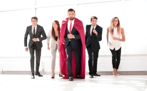 Businessman in superhero cape leading others