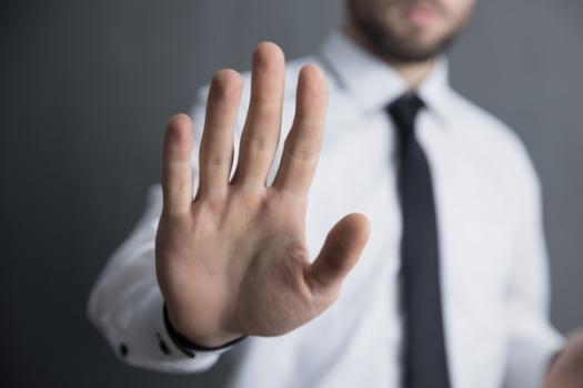 Quick Note: Don’t Sue Your Arbitrator Man with hand raised in Don't or Stop gesture