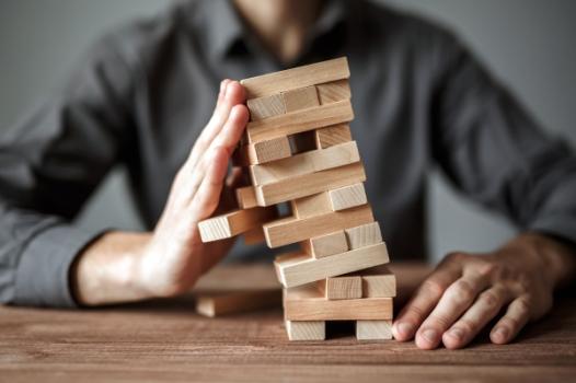 Risk Associated with Design-Build Project Delivery Method Jenga game person holding it up
