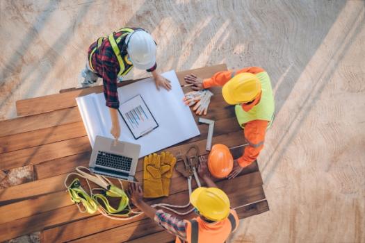 Construction workers at table with tools laptop