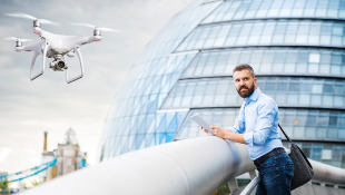 Drone hovering in front of building and man standing at rail