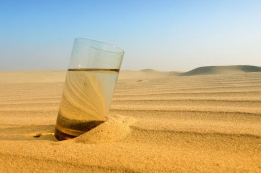 Glass of water in desert