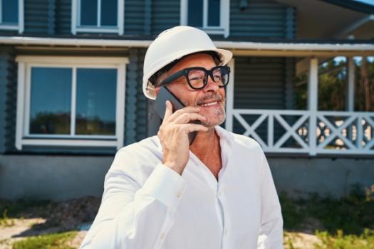 US Homebuilder Sentiment Rises By Most Since 2024 Homebuilder on cell smiling