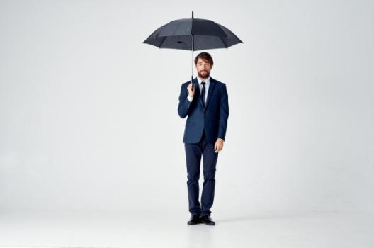 Businessman with umbrella symbolizing coverage